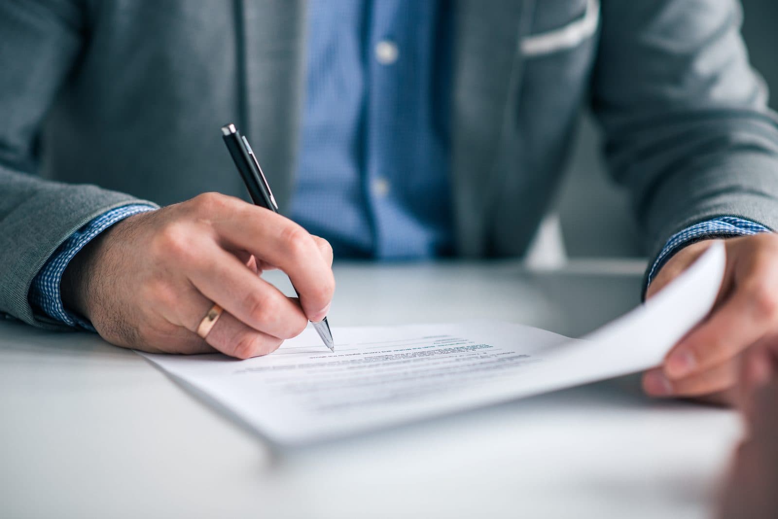 Person signing a printed contract with a pen