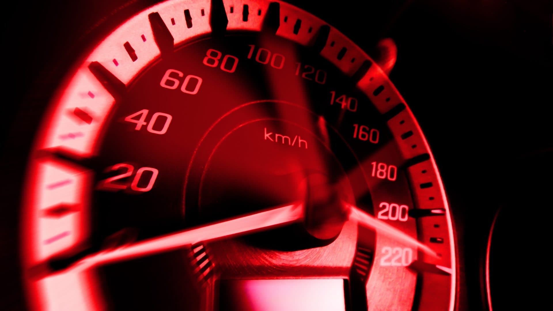 Close-up of an illuminated car speedometer glowing red